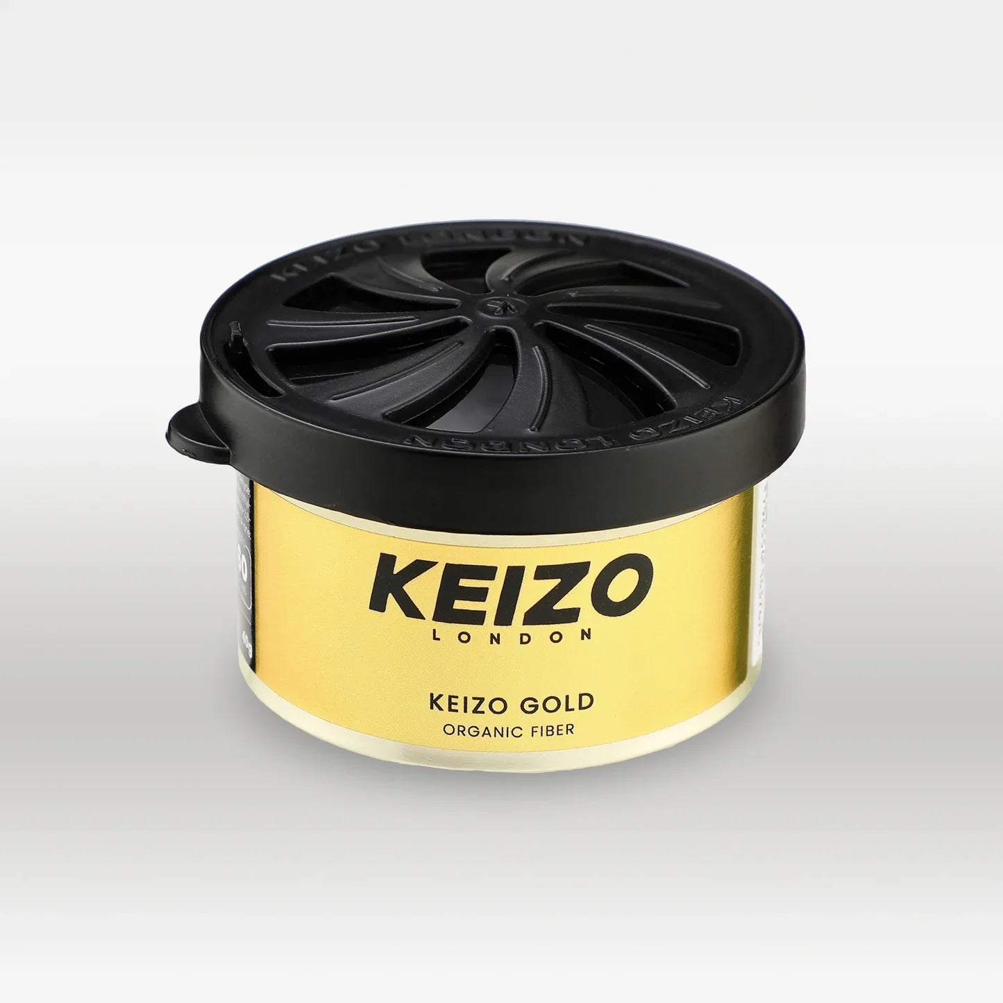 A round gold and black container labeled Keizo London Gold 40g Car Perfume by Keizo, with a black twist-off lid, exudes luxury against a plain white background.