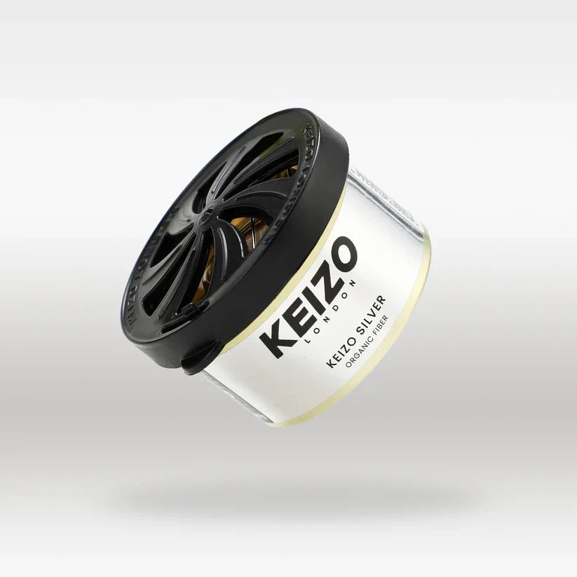 The Keizo London Silver 40g Car Perfume, a round container with a black vented lid, is displayed against a light gray background, highlighting the modern freshness and sleek design of this Keizo brand fragrance.